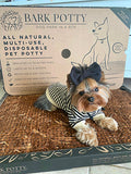 Small Yorkie wearing a striped shirt rests on a Bark Potty disposable dog potty pad.